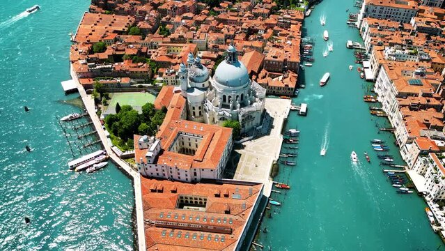 Aerial drone view of Venice, Italy. Water channels with multiple floating and moored boats, historical city centre with Santa Maria della Salute and other old buildings and narrow streets