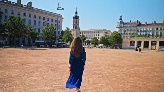 A beautiful girl in a blue dress walking in Place Bellecour Square in Lyon. A tourist female exploring the Old Town of Lyon capital city in France&rsquo;s Auvergne-Rh&ocirc;ne-Alpes region