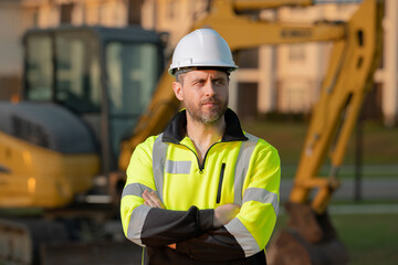 Builder on excavator. Builder worker with excavator. Builder in helmet. Worker in hardhat. Portrait mechanical worker in construction helmet. Engineer builder foreman or repairman.