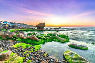 Rocky beach and green moss in sunrise sky at a beautiful beach in central Vietnam. Seascape of Vietnam Strange rocks.