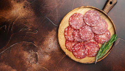 Meat food sausage salami slices on cutting board on aged brown background, mockup. Copy space, flat...