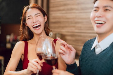 Young happy couple celebrating and toasting with wine glasses in  restaurant.