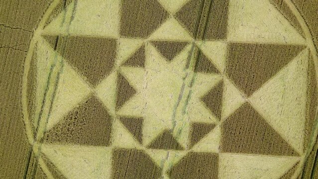 Rising, rotating aerial view above Micheldever circular crop circle pattern on Hampshire agricultural wheat filed