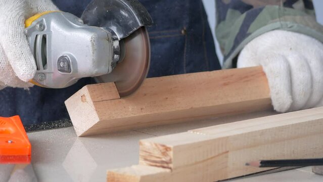 Close-up hands of a man using a Grinding machine sawing cutting wood.