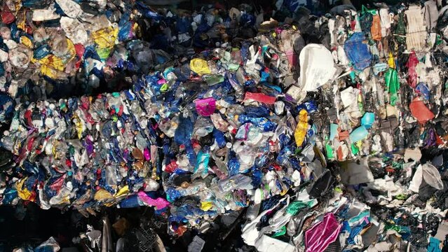 Multiple cubes of compressed multicoloured plastic garbage at waste recycling factory in open air