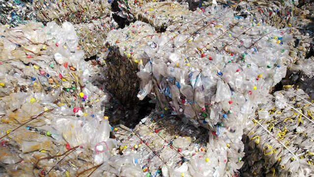 Multiple cubes of compressed transparent plastic garbage at waste recycling factory in open air