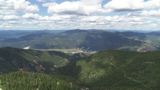 High wide aerial above Kellogg Idaho in summer from forest mountain peaks
