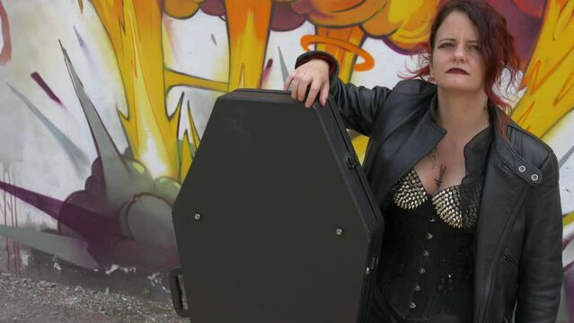 Rocker Girl Standing next to her Coffin guitar case 1. Till up  medium shot slow motion.