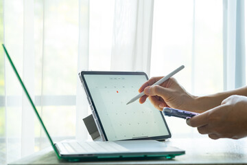 Businessman sets calendar for business meetings and company meetings. taking notes on tablet...