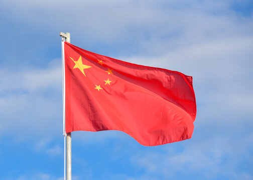 Bandera de China ondeando en el viento contra el cielo azul y nubes  