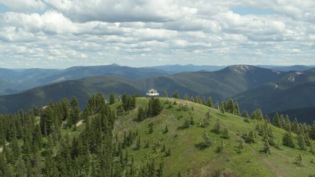 Aerial above white fire lookout tower on mountain peak in northern Idaho in summer