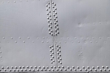 Riveted with button-head rivets metal plate - side of an aircraft - painted in gray as an industrial background