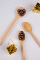Chocolate balls on wooden spoon and brown sugar on wooden spoon on white background.