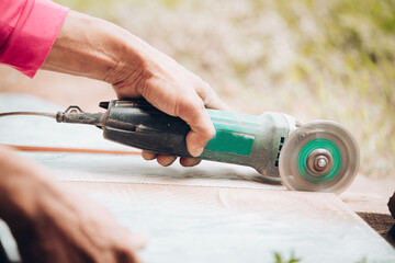 Worker cutting a tile using an angle grinder at construction site. Cutting large ceramic tiles. The...