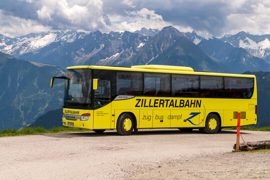 yellow bus of the Zillertalbahn,Zillertaler Verkehrsbetriebe AG in front of the stunning view to the zillertaler alps