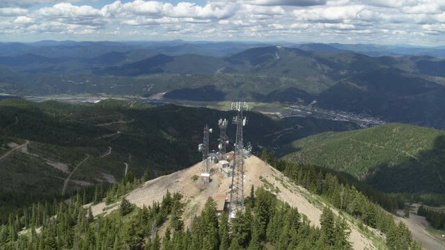 Aerial around cell tower in Kellogg Idaho on peak of mountain in summer