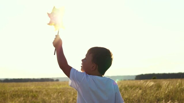 Happy Boy Holding Windmill His Hand. Portrait Boy Smile. Childhood Dream Child. Cheerful Child Holds Spinner Toy His Hand Sunset. Play Game Sunset. Little Son Child Sunset Park Plays With Spinner Toy.