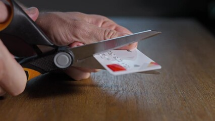 A man cuts a credit card with scissors. Destruction of inactive bank cards in order to increase financial security.