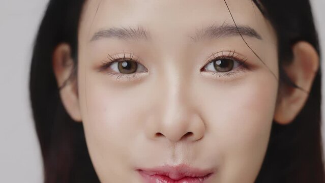 Close up portrait beautiful young Asian woman with healthy facial skin opening eyes.