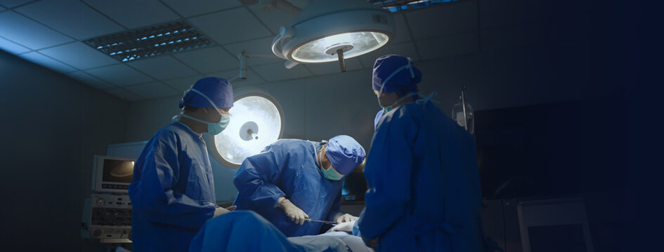 Medical Team Performing Surgical Operation in Modern Operating Room.Surgeons team working with Monitoring of patient in surgical,, dark background.The theater of the operating room