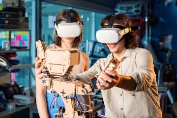 Fototapeta na wymiar Young man and woman in VR glasses doing experiments in robotics in a laboratory