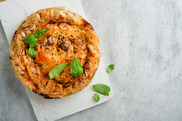 Delicious pie Spanakopita with soft feta cheese and spinach on old gray concrete table backgrounds....