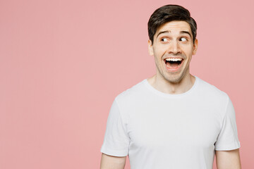 Young surpirsed shocked man wear white t-shirt casual clothes look aside on workspace area mock up with opened mouth isolated on plain pastel light pink background studio portrait. Lifestyle concept. - obrazy, fototapety, plakaty