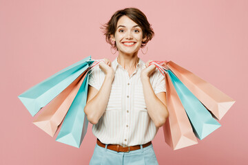 Young smiling happy fun cheerful woman wear casual clothes hold shopping paper package bags look camera isolated on plain light pastel pink color background studio. Black Friday sale buy day concept.