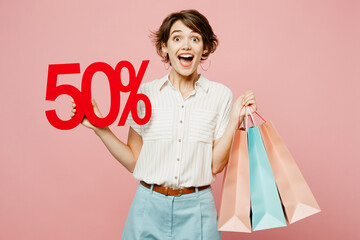Young surprised shocked woman wear casual clothes hold shopping paper package bags show 50 percent...