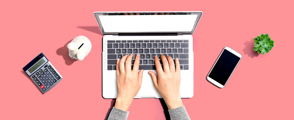 Woman using a laptop computer with a piggy bank and a calculator