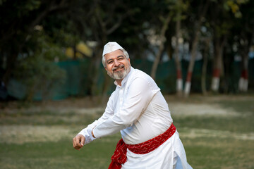 Happy indian senior man in traditional wear and dancing at garden
