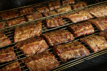 Grilled barbecue pork ribs in a smoker at the factory. The concept of a delicious snack for a picnic or a country house.