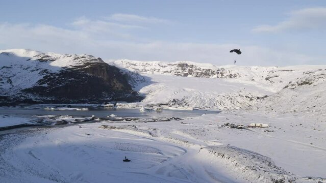 Aerial shot of parachuters landing within a frozen mountain valley in Iceland