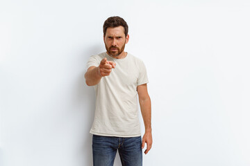 Indignant man standing over white background pointing displeased and angry to you on camera 