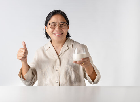 Asian senior woman drinking milk happily - Powered by Adobe