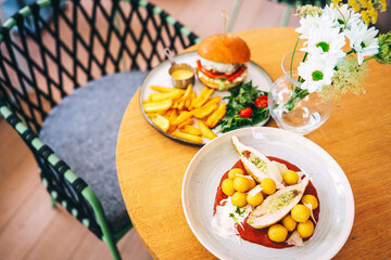 two high-calorie meals on the cafe table. chicken platter and burger platter on restaurant wooden table