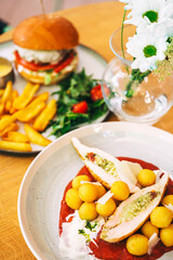 two high-calorie meals on the cafe table. chicken platter and burger platter on restaurant wooden table