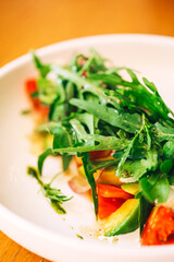 fresh salad with arugula and avocado on the table. refreshing salad with fresh herbs and vegetables