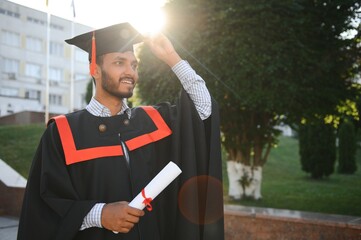 Young indian graduated boy holding his graduation degree convocation ceremony. student graduate...