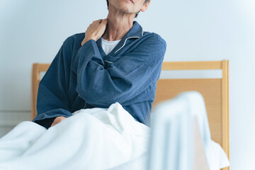 ベッドで起き上がって疲れに悩むシニア男性