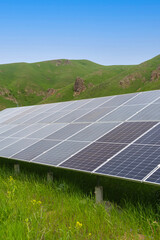 Close-up of solar panels against the background of green mountains, blue sky on a summer day....