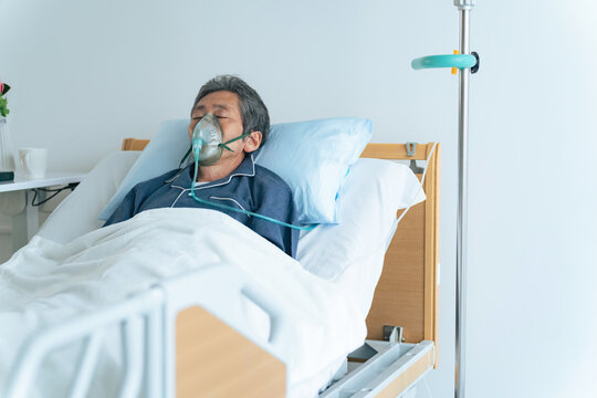酸素マスクをつけてベッドに寝るシニア男性
