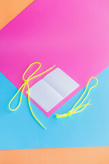 The school notebook lies on a pink, blue and orange background with empty pages. - 630642432