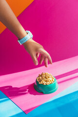 Hand trying to take cereals corn flakes or rings from a bowl on colorful background - 630642634