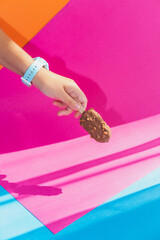 Hand hold chocolate ice cream on stick on colorful background - 630642645