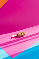 Chocolate ice cream on stick laying on colorful background. Pop art barbie style, minimalism concept - 630642697
