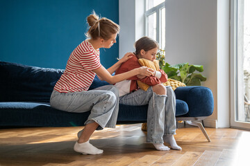 Affectionate mom trying to establish contact with teenage daughter sitting on couch at home....