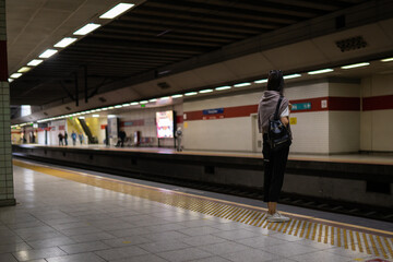Young woman waits at metro station while the train arrives