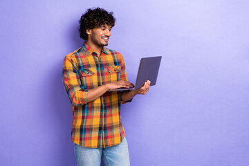 Photo of positive guy use wireless netbook coworking empty space ad promo isolated on violet color...