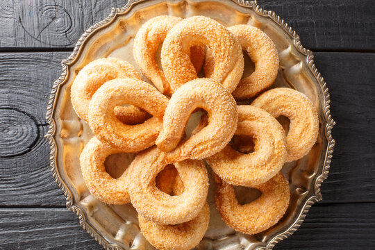 Italian cookies Piedmontese Torcetti sprinkled with sugar close-up on a plate on the table. Horizontal top view from above